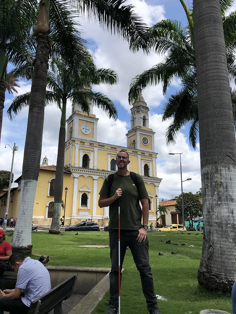 Felipe Gutiérrez con su bastón blanco y rojo frente a la iglesia de San Laureano en Bucaramanga