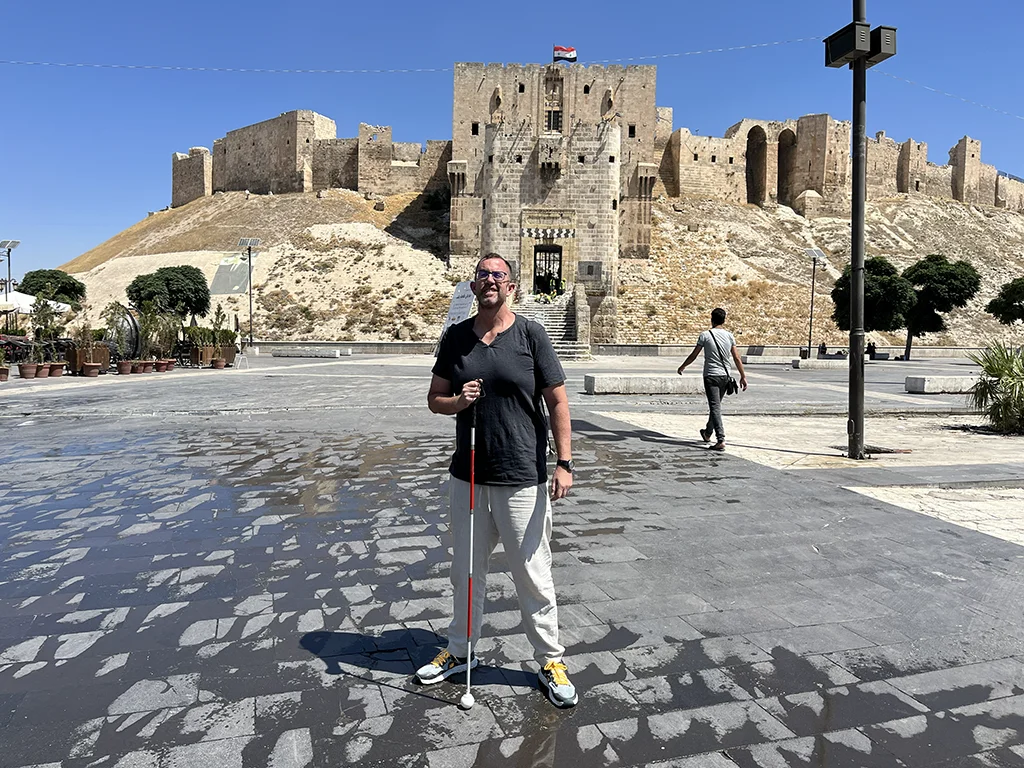 Felipe, viajero con sordoceguera caminando con bastón por las calles de Alepo, Siria