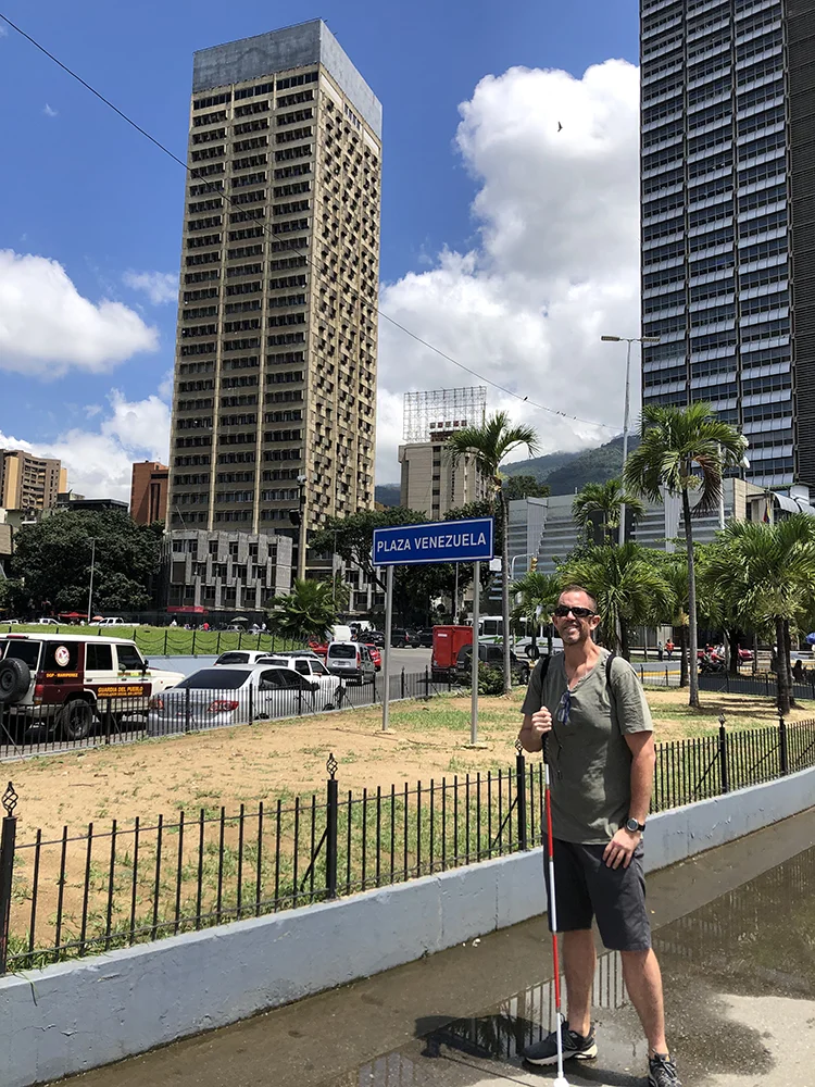 Felipe con su bastón blanco y rojo en Plaza Venezuela durante su viaje a Caracas