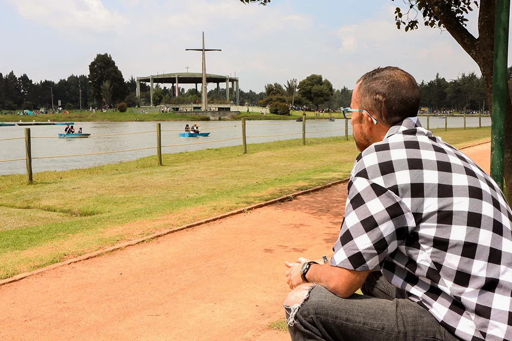 Persona con sordoceguera sentada en un parque utilizando un audífono